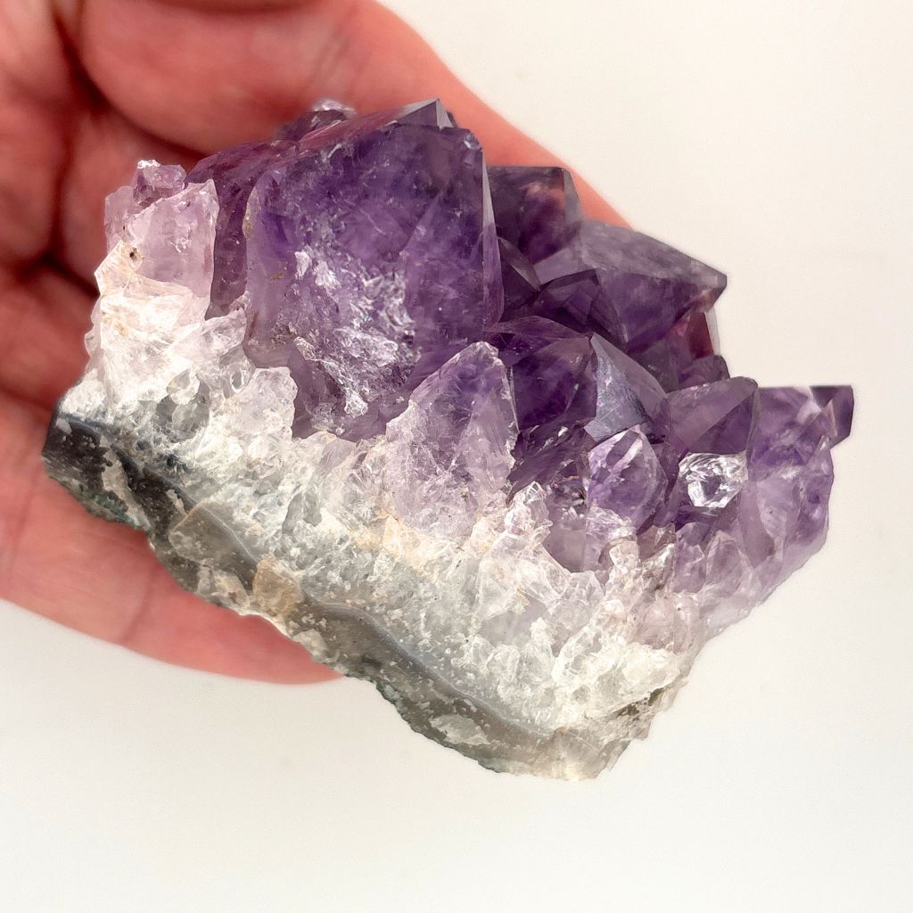 Natural Amethyst crystal cluster with deep purple crystal points growing on a natural quartz matrix, polished by nature and ideal for display or meditation.