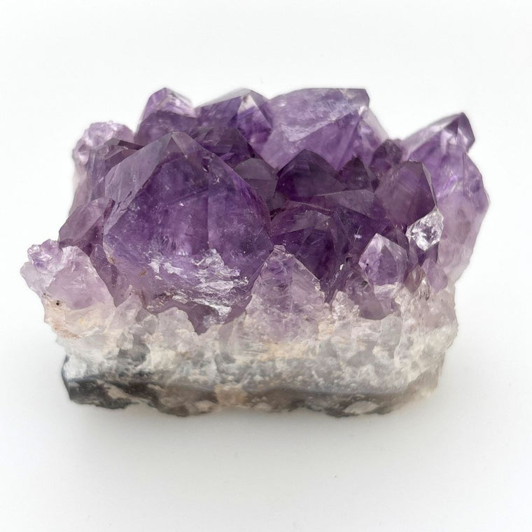 Natural Amethyst crystal cluster with deep purple crystal points growing on a natural quartz matrix, polished by nature and ideal for display or meditation.