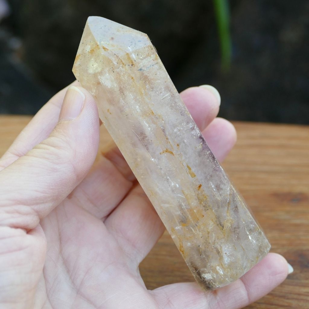 Polished Clear Quartz crystal point with natural mineral inclusions and golden earthy tones