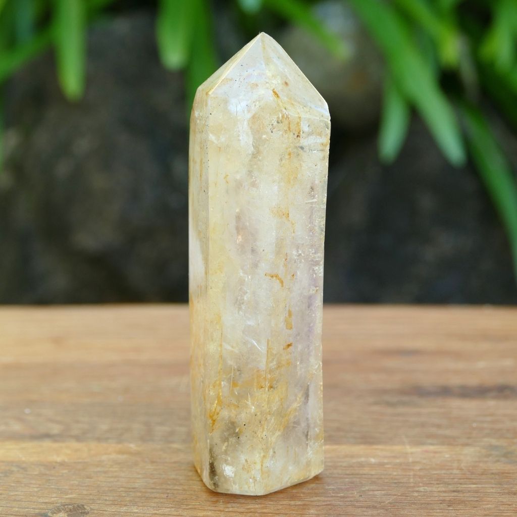 Polished Clear Quartz crystal point with natural mineral inclusions and golden earthy tones