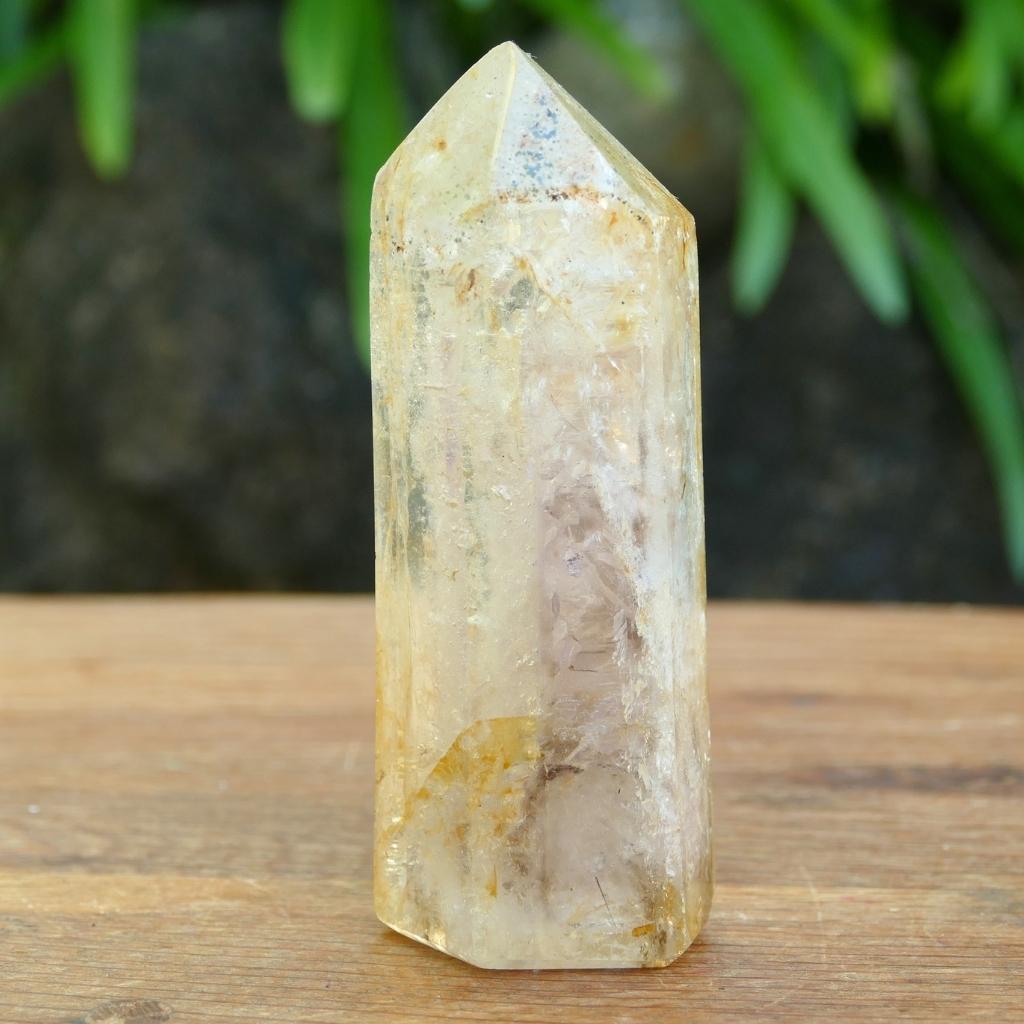 Polished Clear Quartz crystal point with natural mineral inclusions and golden earthy tones