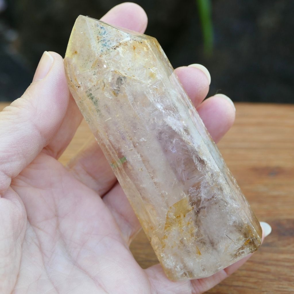 Polished Clear Quartz crystal point with natural mineral inclusions and golden earthy tones