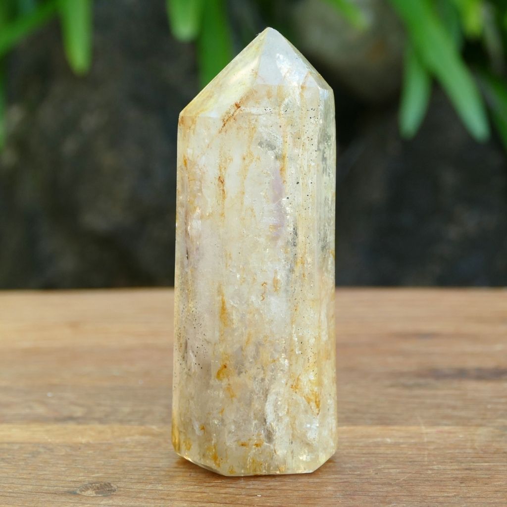 Polished Clear Quartz crystal point with natural mineral inclusions and golden earthy tones