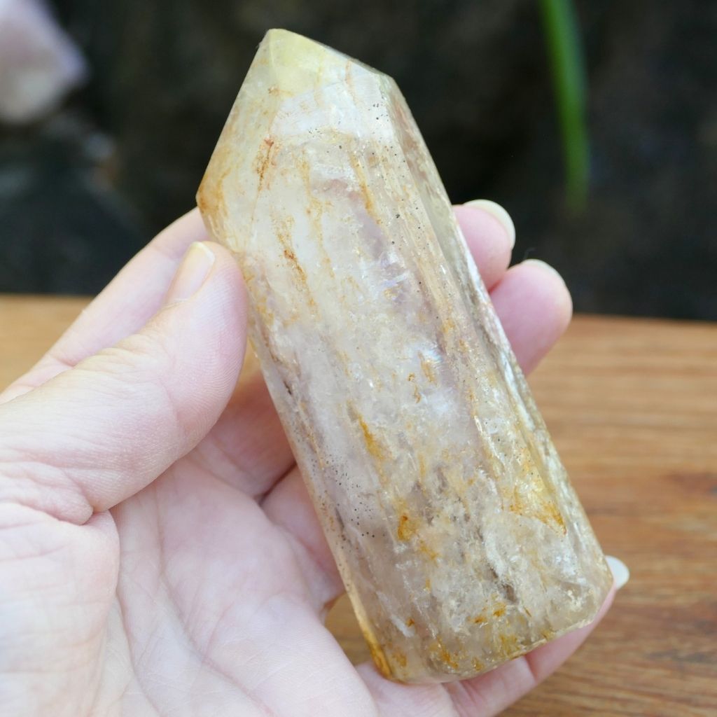 Polished Clear Quartz crystal point with natural mineral inclusions and golden earthy tones