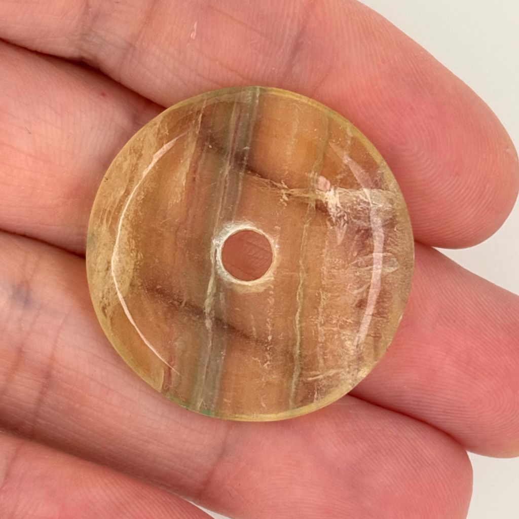 Natural Rainbow Fluorite donut pendant with green, purple and cream banding, polished into a traditional Pi disc shape.