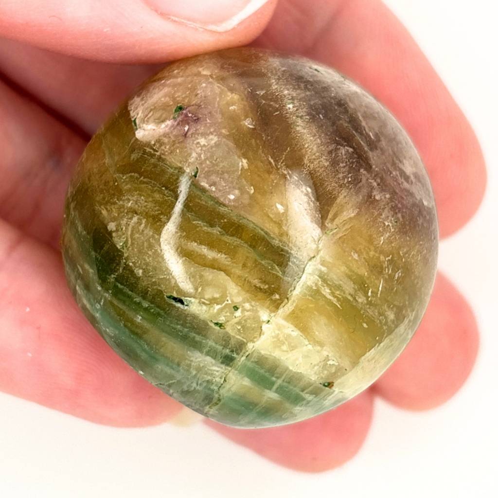 Polished Fluorite crystal sphere with green, gold and lavender natural banding and flat cut base for display